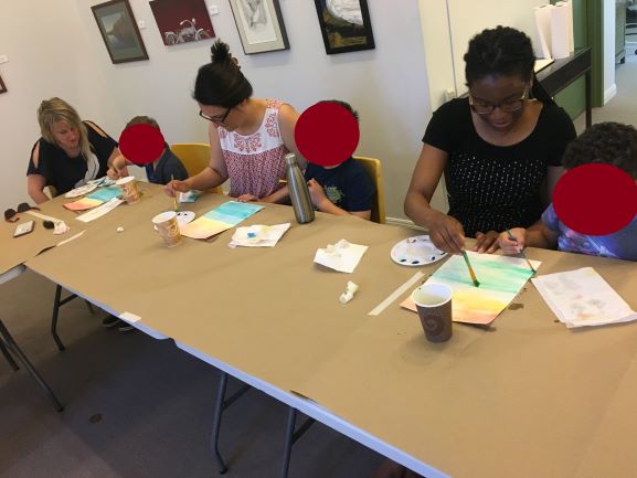 Families work together to create a painting in the art gallery